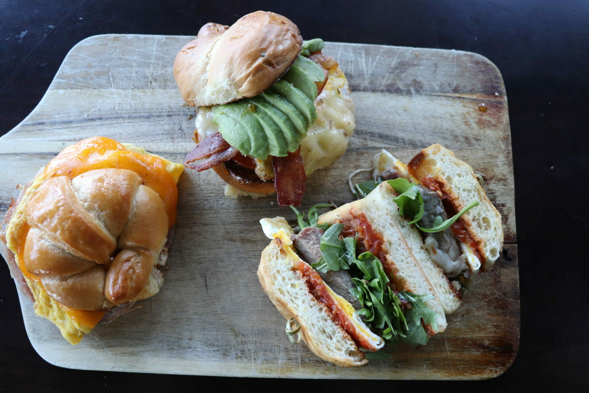 Three breakfast sandwiches on cutting board