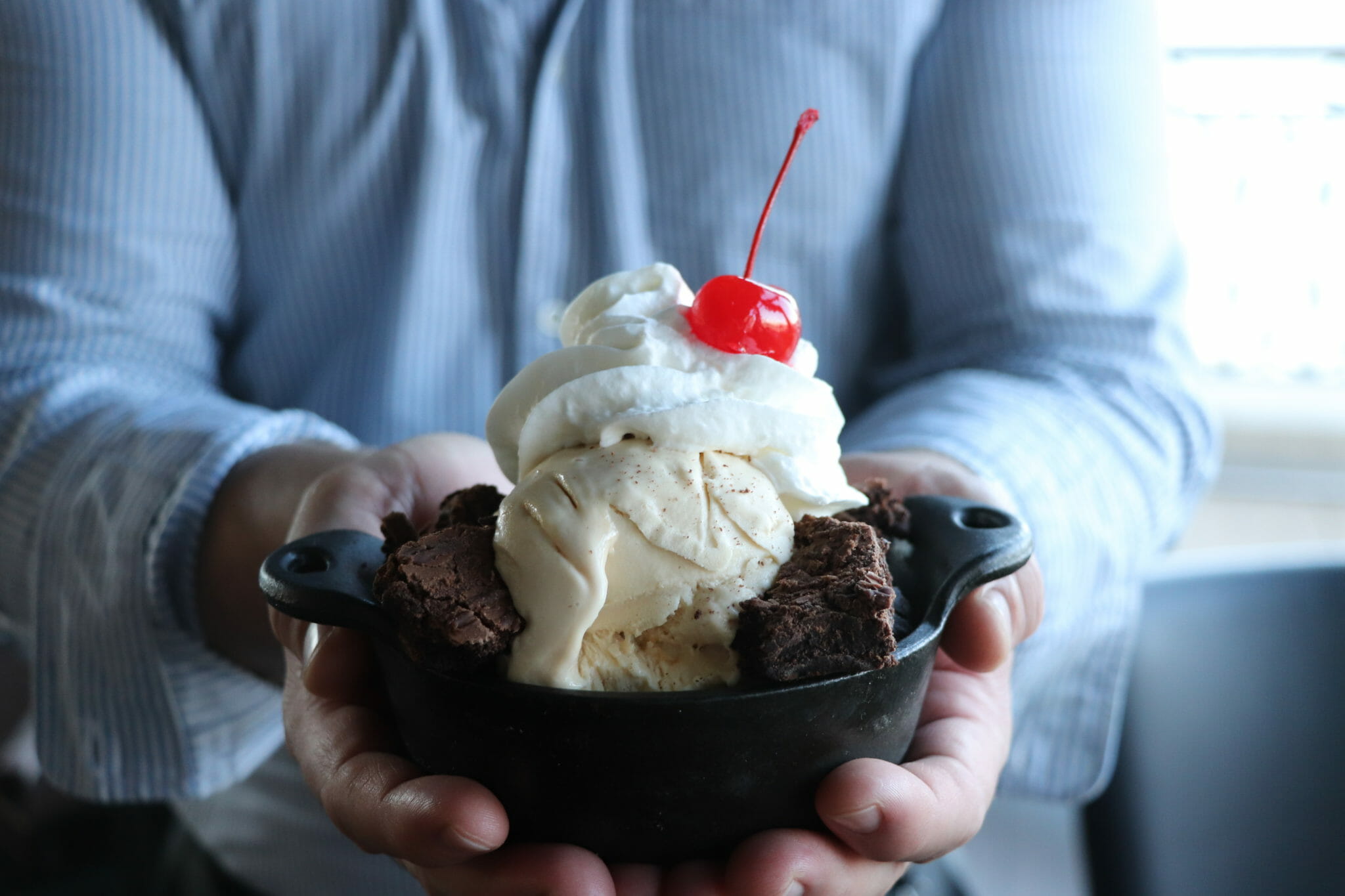 Hands holding brownie sundae